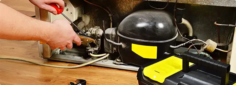 Refrigerator repair technician fixing the compressor and wiring in Coker, AL