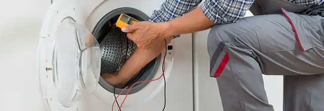 Dryer repair technician inspecting and repairing a clothes dryer in Tuscaloosa, AL