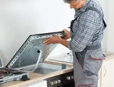 Appliance repair technician installing a built-in cooktop in Tuscaloosa, AL