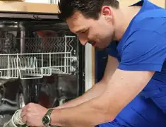 Dishwasher repair technician inspecting and servicing an open dishwasher in Tuscaloosa, AL
