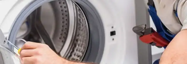 Appliance technician repairing a clothes dryer drum and internal parts in Tuscaloosa, AL
