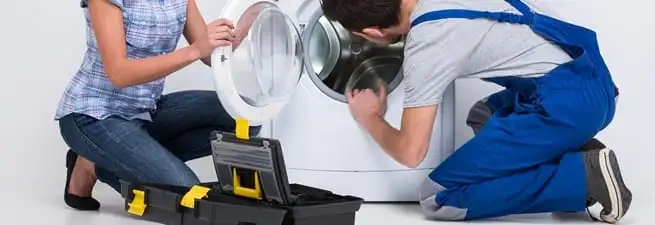 Washer repair technician inspecting a front-load washing machine with tools in Tuscaloosa, AL