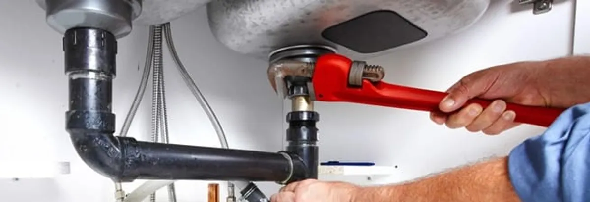 Garbage disposal repair technician tightening the sink drain and disposal connection in Tuscaloosa, AL