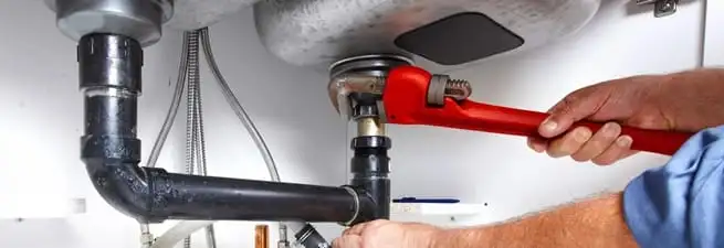 Garbage disposal repair technician tightening the sink drain and disposal connection in Tuscaloosa, AL