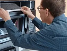 Appliance repair technician replacing a microwave vent filter in Tuscaloosa, AL