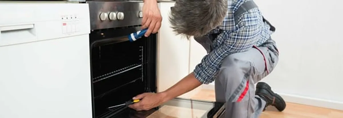 Oven repair technician inspecting and servicing an electric oven in Tuscaloosa, AL