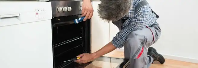 Oven repair technician inspecting and servicing an electric oven in Tuscaloosa, AL