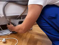 Appliance repair technician fixing refrigerator water line and connections in Tuscaloosa, AL