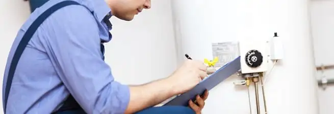 Water heater repair technician inspecting the unit and recording service notes in Tuscaloosa, AL