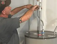 Water heater repair technician tightening supply line connections in Tuscaloosa, AL