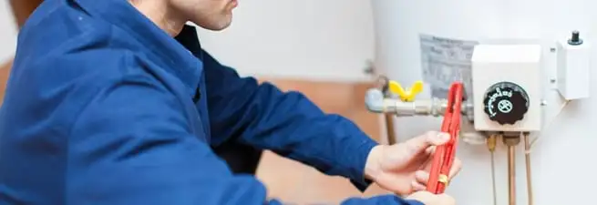 Water heater repair technician adjusting the temperature control and gas valve in Tuscaloosa, AL